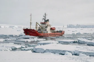 Bateau d'expédition à coque rouge naviguant dans les glaces arctiques du pôle Nord