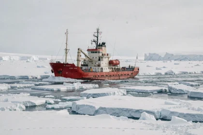 Bateau d'expédition à coque rouge naviguant dans les glaces arctiques du pôle Nord