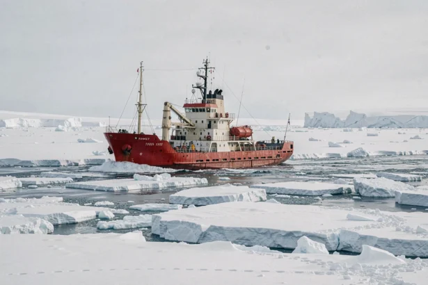 Bateau d'expédition à coque rouge naviguant dans les glaces arctiques du pôle Nord