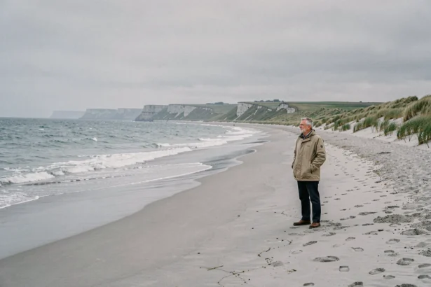 Un visiteur contemplatif debout sur la plage d'Omaha Beach en Normandie, paysage côtier historique du débarquement