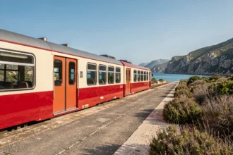 Petit train régional de Corse à quai entre Île-Rousse et Calvi avec vue sur la mer Méditerranée